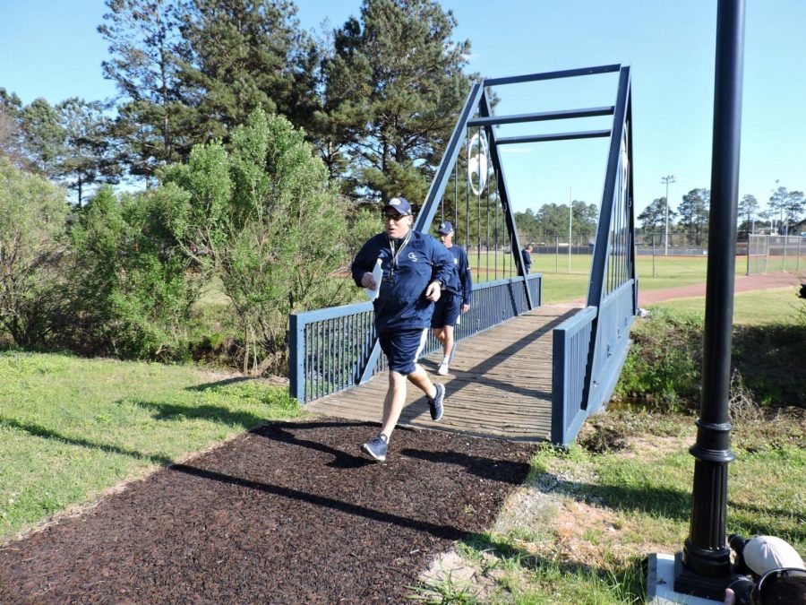 Head Coach Chad Lunsford runs across the bridge at Eagle Creek for the first practice of spring.