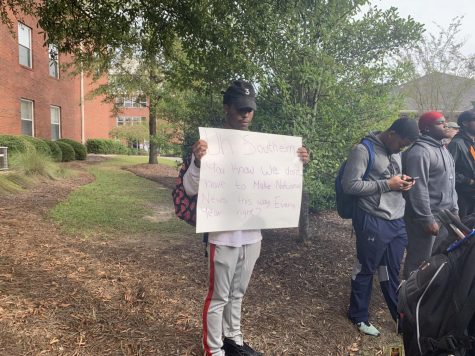 Zeke Mincey, a junior business management major, holds a sign at Fridays protest at Eagle Village. 