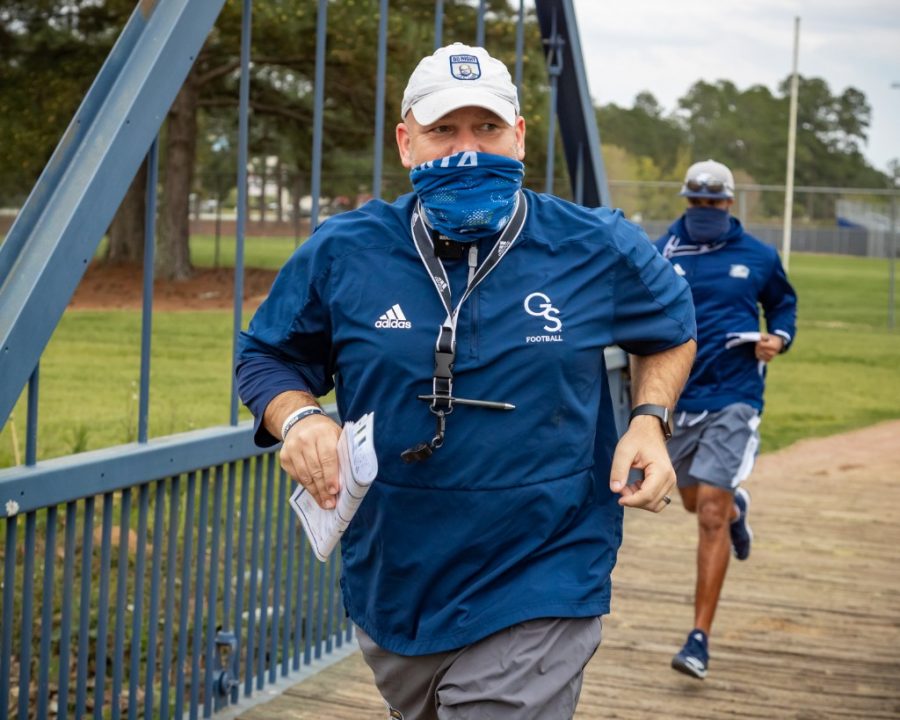 Chad Lunsford runs with his team over the Beautiful Eagle Creek bridge to get to the practice field on March 24. Eagle Creek is said to have magical properties by legend coach Erk Russel, and the drainage ditch named Beautiful Eagle Creek has since become an important part of game day traditions.