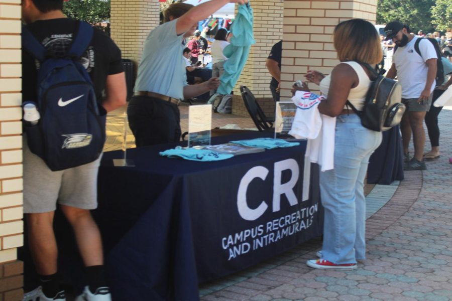 The Campus Recreation and Intramurals table is passing out t-shirts to students and taking the opportunity to share all of the fun activities they offer.