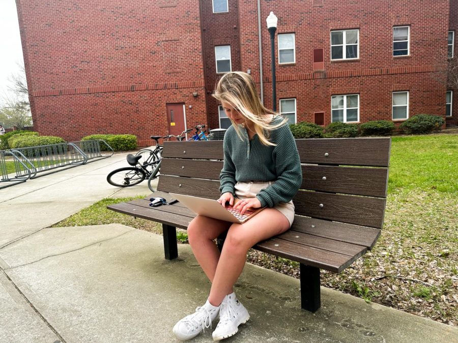 Freshman, Faith Cale enjoys the sun and fresh air while working on a homework assignment outside of Centennial Place 3 on March 3.